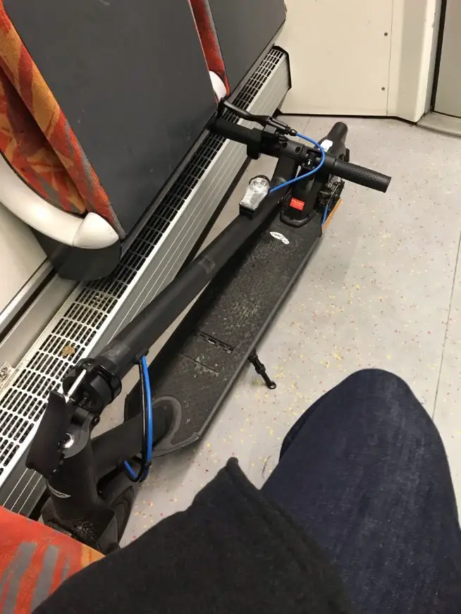folded scooter on the floor of a train next to seats